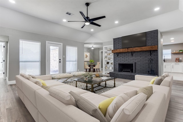 living room with a wealth of natural light, built in shelves, wood finished floors, and visible vents