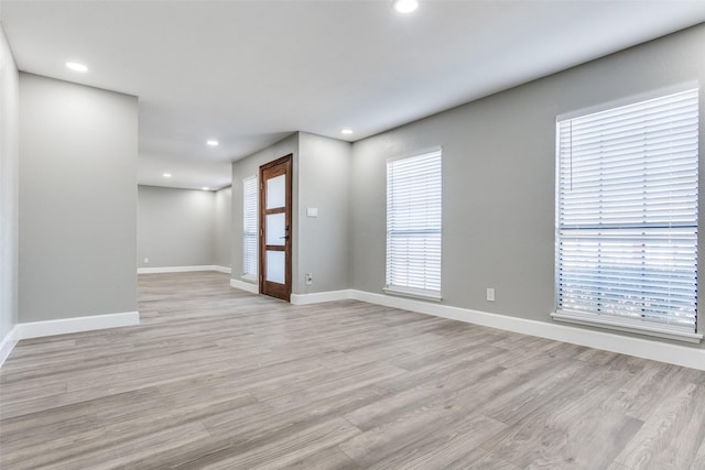 spare room with recessed lighting, baseboards, and light wood finished floors