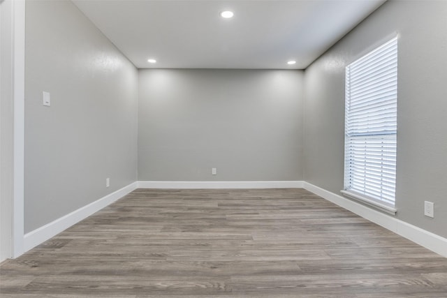 spare room featuring recessed lighting, wood finished floors, and baseboards