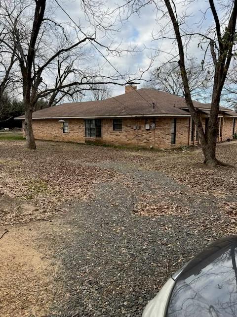 back of property featuring brick siding and a chimney