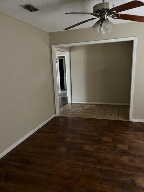 unfurnished room featuring baseboards, visible vents, ceiling fan, wood finished floors, and a textured ceiling