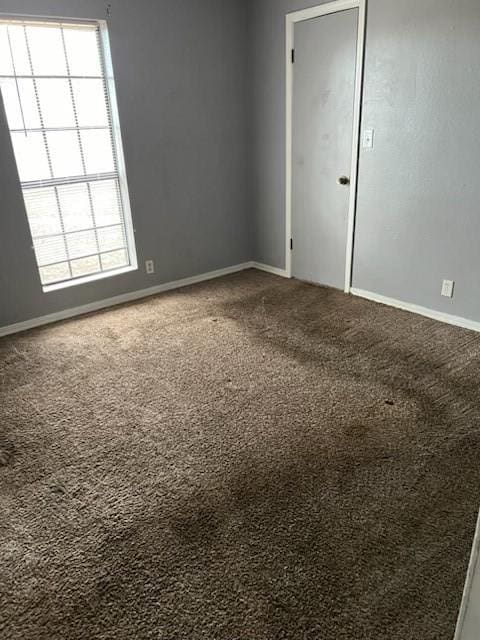 unfurnished room with a healthy amount of sunlight, carpet, and baseboards