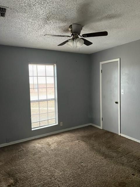 spare room with baseboards, carpet floors, visible vents, and a ceiling fan