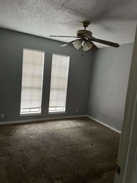 empty room featuring a textured ceiling, carpet, a ceiling fan, and baseboards