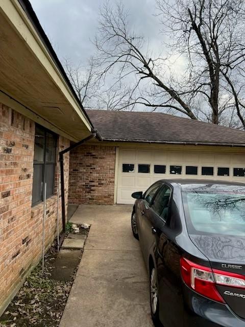 view of property exterior featuring a garage, crawl space, roof with shingles, and brick siding