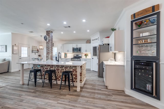 kitchen with beverage cooler, visible vents, a breakfast bar area, stainless steel appliances, and crown molding