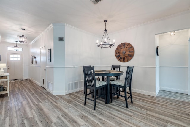 dining area featuring a chandelier, crown molding, and wood finished floors