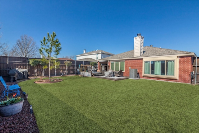 rear view of property featuring brick siding, a yard, central air condition unit, fence, and a deck