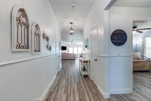 hallway with ornamental molding, baseboards, and wood finished floors