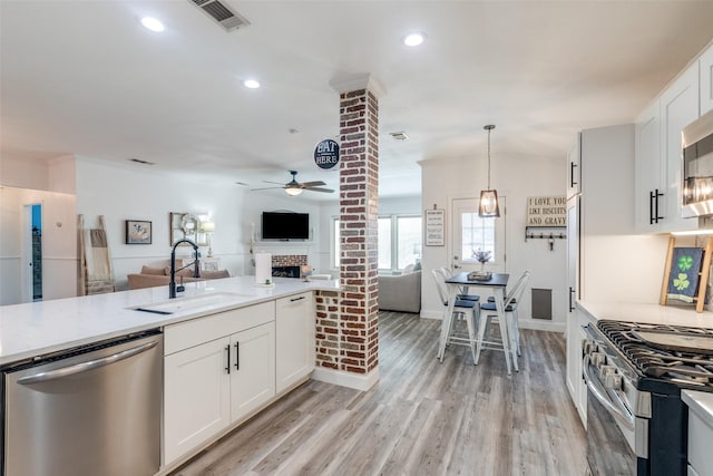 kitchen featuring visible vents, appliances with stainless steel finishes, open floor plan, ornate columns, and a sink