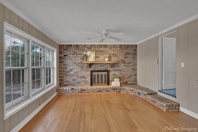 unfurnished living room with ornamental molding, a brick fireplace, brick wall, and wood finished floors