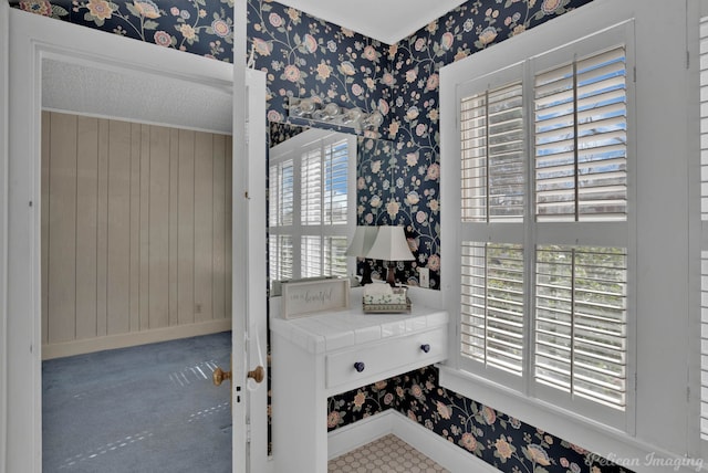 interior space featuring baseboards, a healthy amount of sunlight, and wallpapered walls