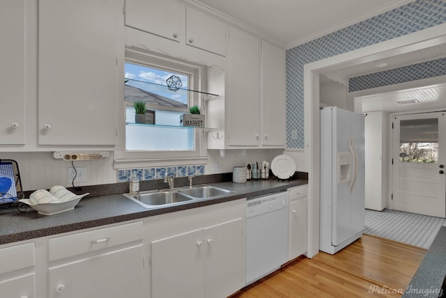 kitchen with dark countertops, white appliances, wallpapered walls, and a sink