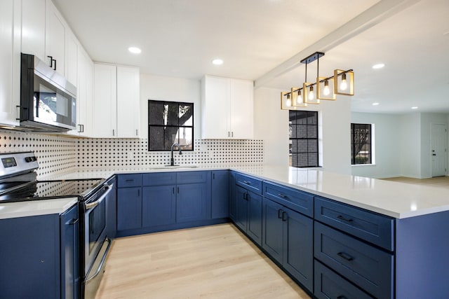 kitchen featuring a peninsula, appliances with stainless steel finishes, a sink, and blue cabinets