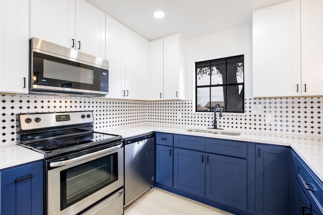 kitchen with stainless steel appliances, a sink, white cabinets, and blue cabinets