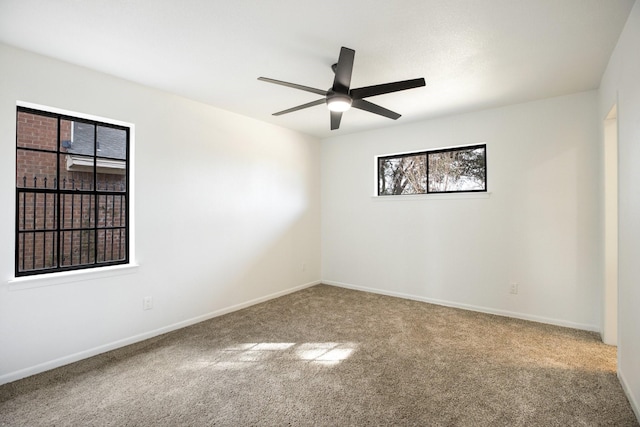 empty room with ceiling fan, carpet, and baseboards