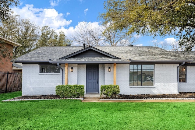 view of front of house with a front lawn, a shingled roof, fence, and brick siding