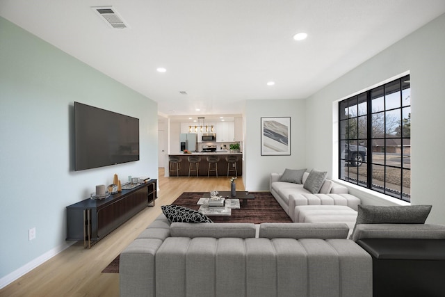 living area with baseboards, light wood finished floors, visible vents, and recessed lighting