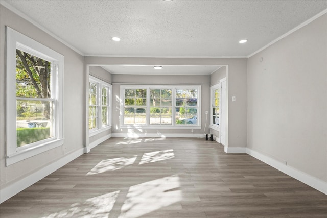 unfurnished living room featuring a textured ceiling, crown molding, baseboards, and wood finished floors