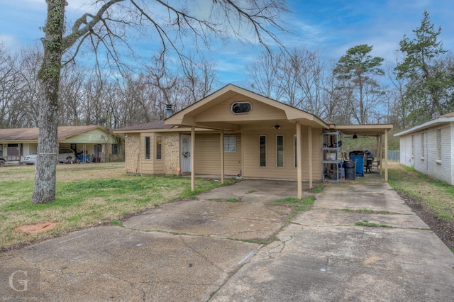 view of front of property with brick siding, a chimney, concrete driveway, a carport, and a front lawn