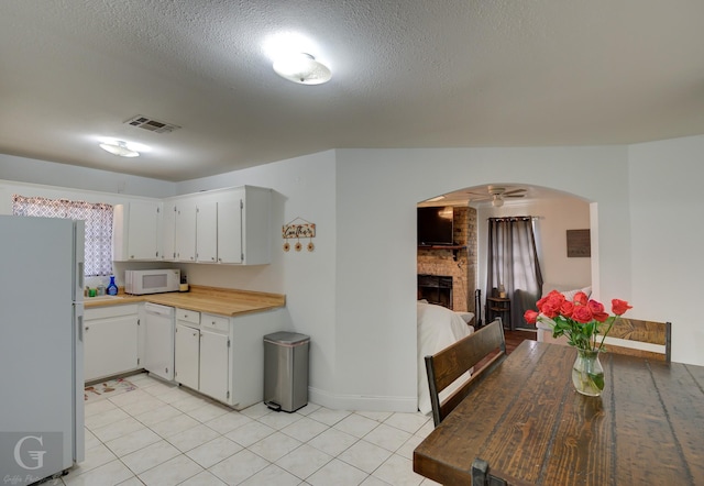 kitchen featuring arched walkways, light tile patterned floors, white appliances, visible vents, and light countertops