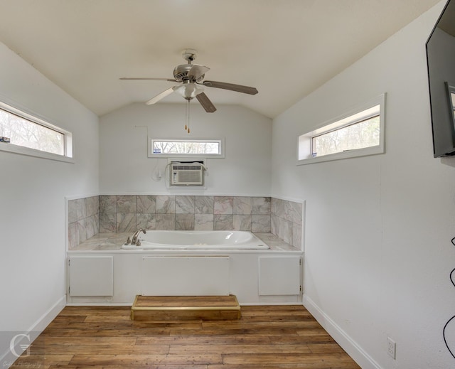 bathroom with vaulted ceiling, plenty of natural light, and a bath