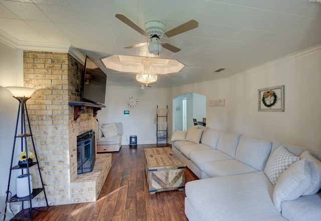 living room featuring arched walkways, a fireplace, wood finished floors, a ceiling fan, and crown molding