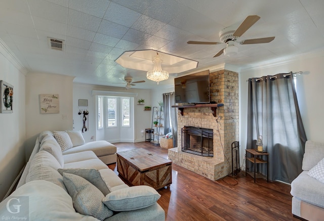 living area featuring a fireplace, wood finished floors, visible vents, baseboards, and crown molding