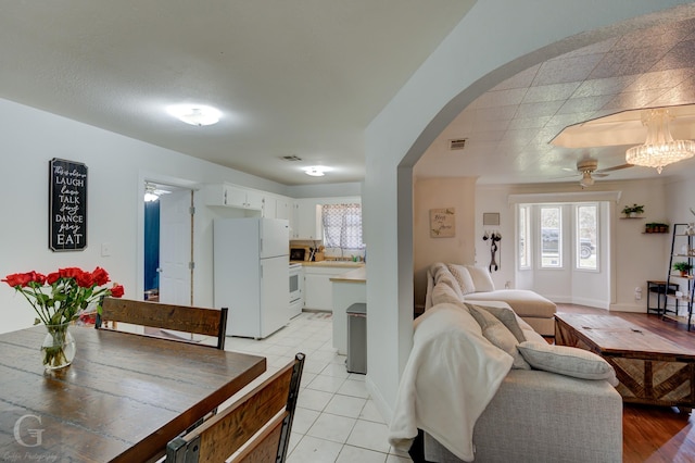 interior space with arched walkways, light tile patterned flooring, visible vents, a ceiling fan, and baseboards