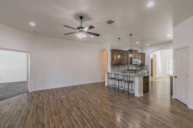 kitchen featuring appliances with stainless steel finishes, arched walkways, open floor plan, and visible vents