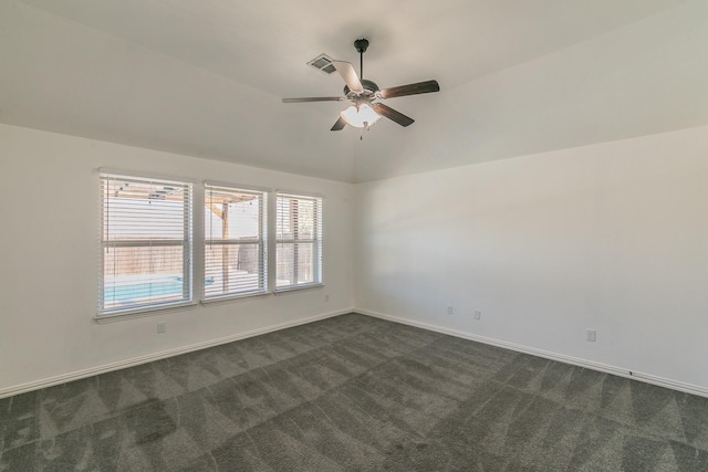 empty room with visible vents, baseboards, a ceiling fan, vaulted ceiling, and dark carpet