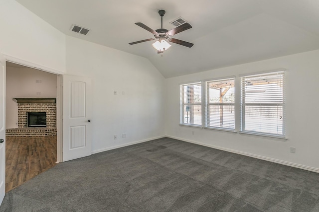 unfurnished living room featuring visible vents, ceiling fan, vaulted ceiling, dark colored carpet, and a brick fireplace