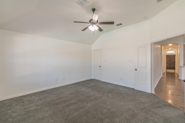 empty room featuring baseboards, visible vents, arched walkways, and dark colored carpet