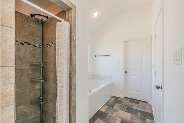 full bath with vaulted ceiling, stone finish floor, a tile shower, and a bath