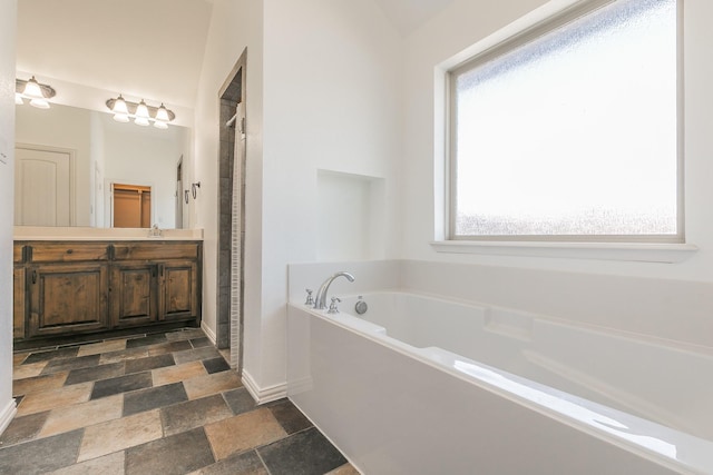 full bathroom featuring vanity, baseboards, a shower stall, a bath, and stone finish floor