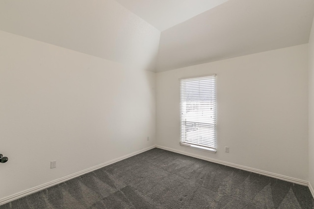 unfurnished room featuring lofted ceiling, baseboards, and dark colored carpet