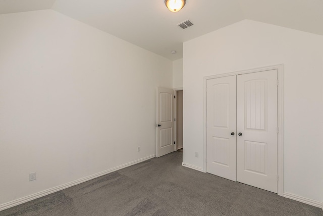 unfurnished bedroom with lofted ceiling, dark colored carpet, visible vents, and baseboards