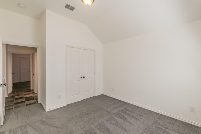 unfurnished bedroom with a closet, visible vents, carpet flooring, vaulted ceiling, and baseboards