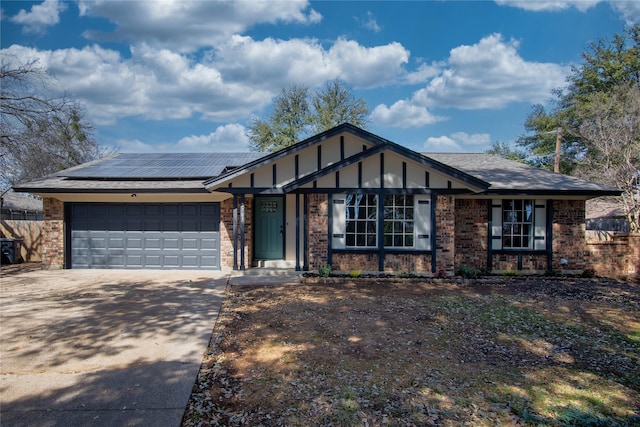 view of front of home with solar panels, concrete driveway, brick siding, and an attached garage