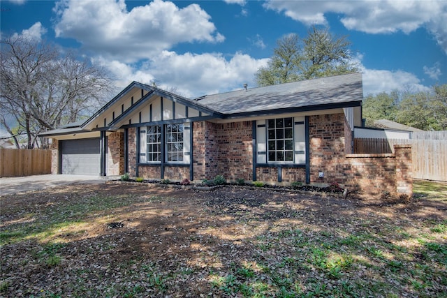 view of front of property featuring driveway, brick siding, an attached garage, and fence