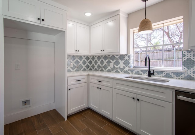 kitchen featuring dishwasher, light countertops, a sink, and decorative backsplash