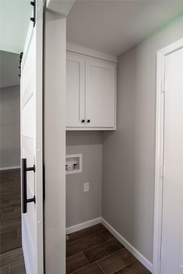 washroom featuring a barn door, hookup for a washing machine, baseboards, cabinet space, and wood tiled floor