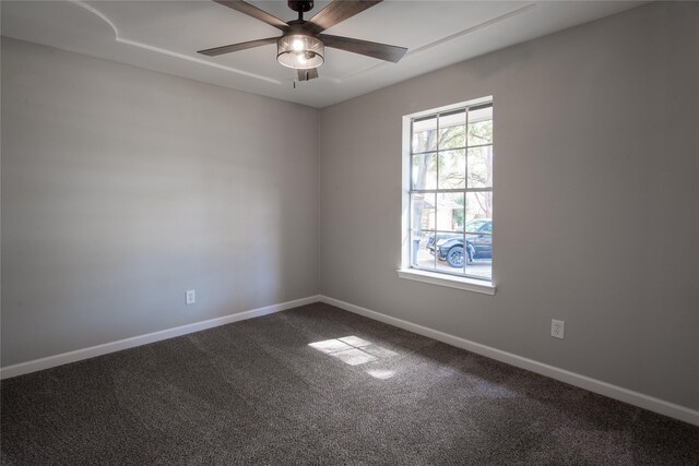 empty room featuring baseboards, dark carpet, and ceiling fan