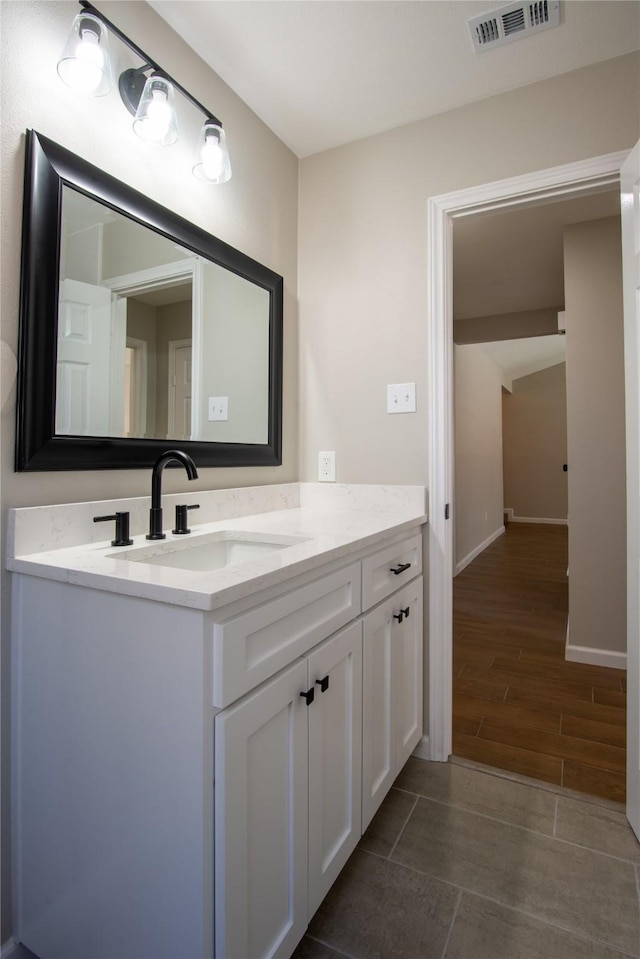 bathroom featuring wood tiled floor, visible vents, vanity, and baseboards