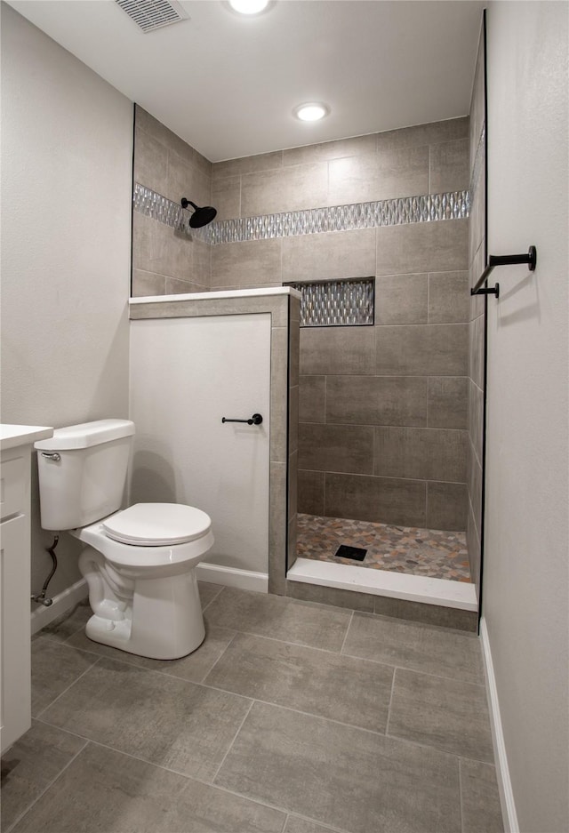 bathroom with a walk in shower, toilet, visible vents, vanity, and baseboards