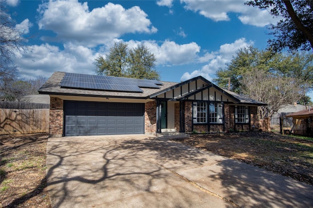 view of front of house featuring a garage, roof mounted solar panels, fence, and driveway