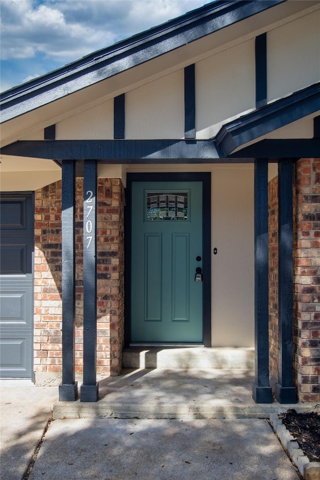 view of exterior entry featuring brick siding and an attached garage