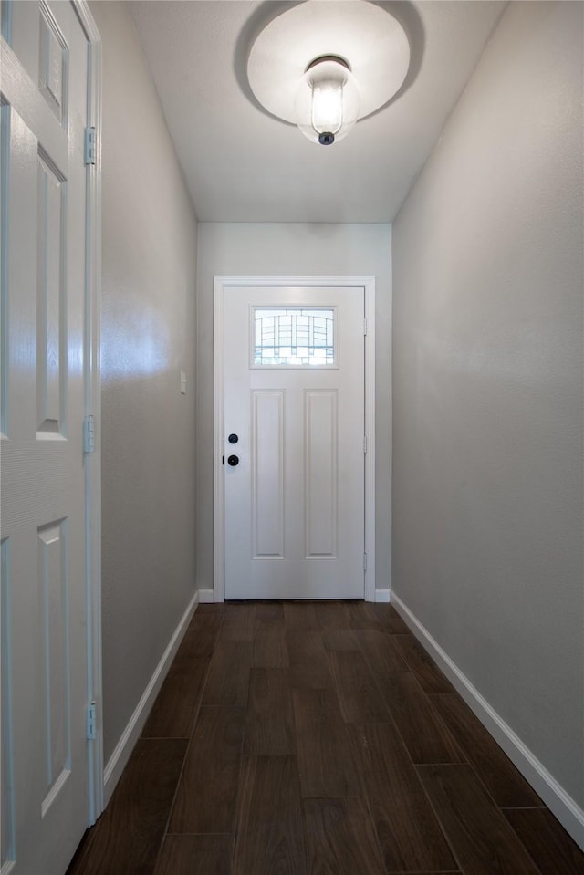 doorway featuring dark wood-style flooring and baseboards