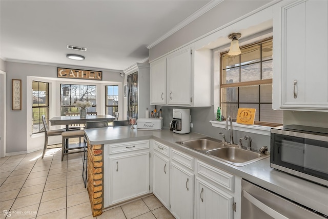 kitchen featuring light tile patterned floors, stainless steel appliances, a sink, visible vents, and ornamental molding