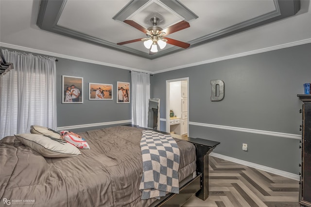 bedroom featuring a raised ceiling, crown molding, baseboards, and ensuite bathroom